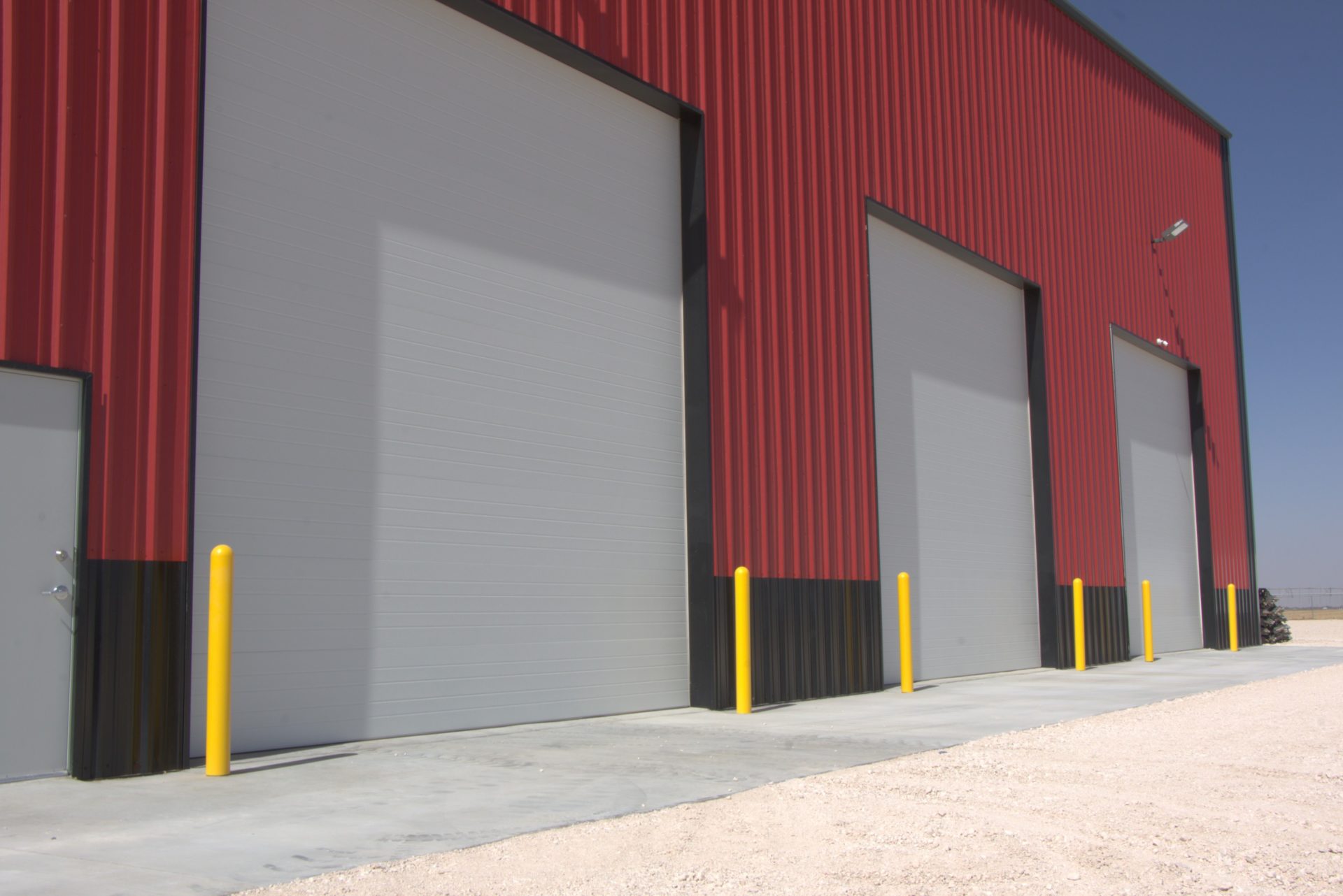 Commercial building with three gray overhead doors in loading area
