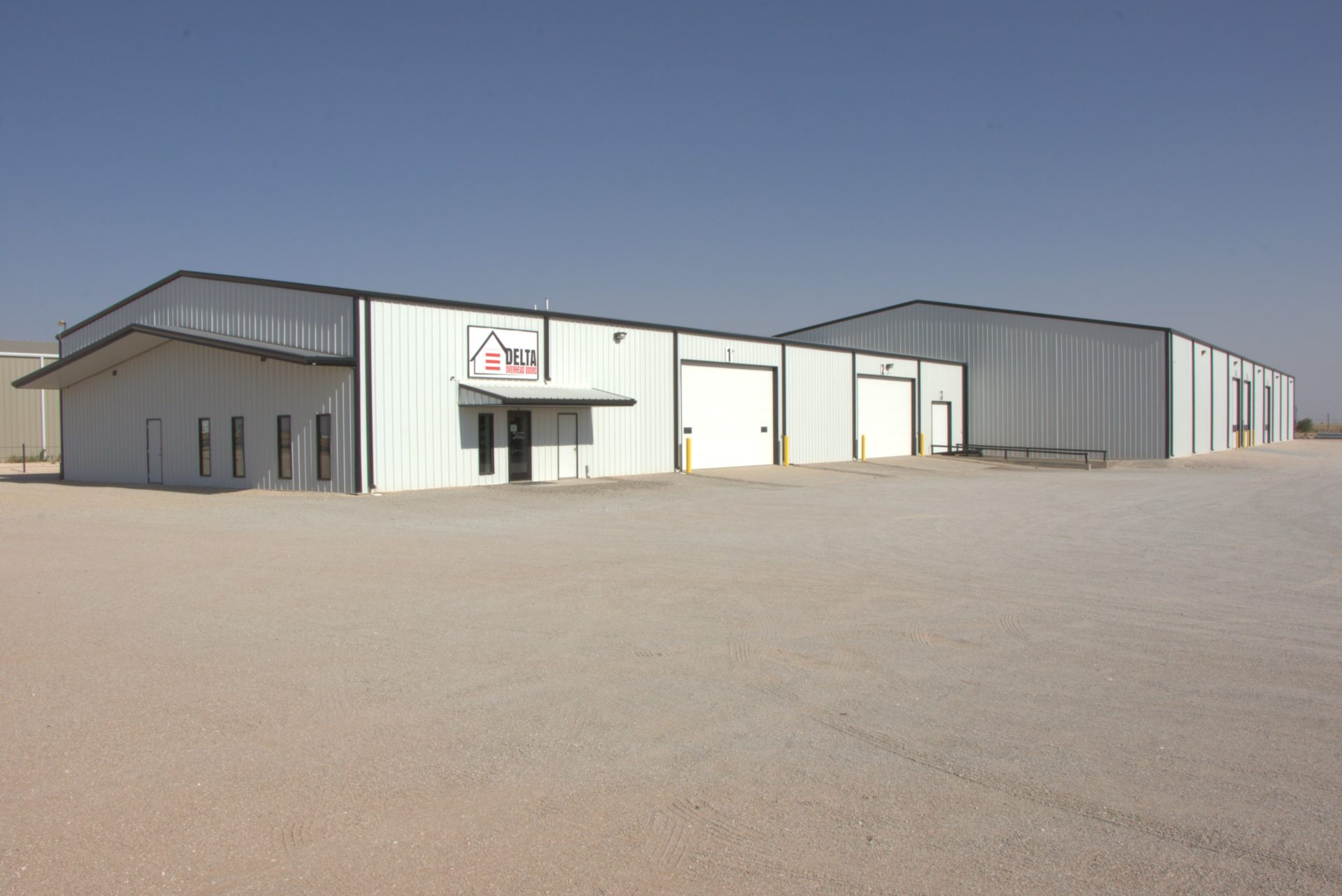 Two metal commercial buildings, one with two white overhead doors