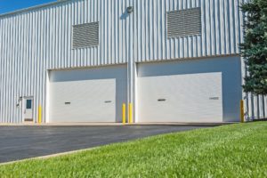 Two white overhead doors at a large commercial building's loading area