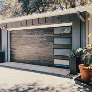 Wood garage door with four window panels on blue-gray detached garage