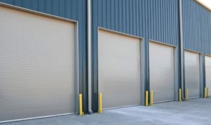 Three steel overhead doors rolled down at blue commercial building
