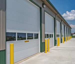 Micro-grooved overhead doors with rows of four window panels, all lining a light brown commercial building